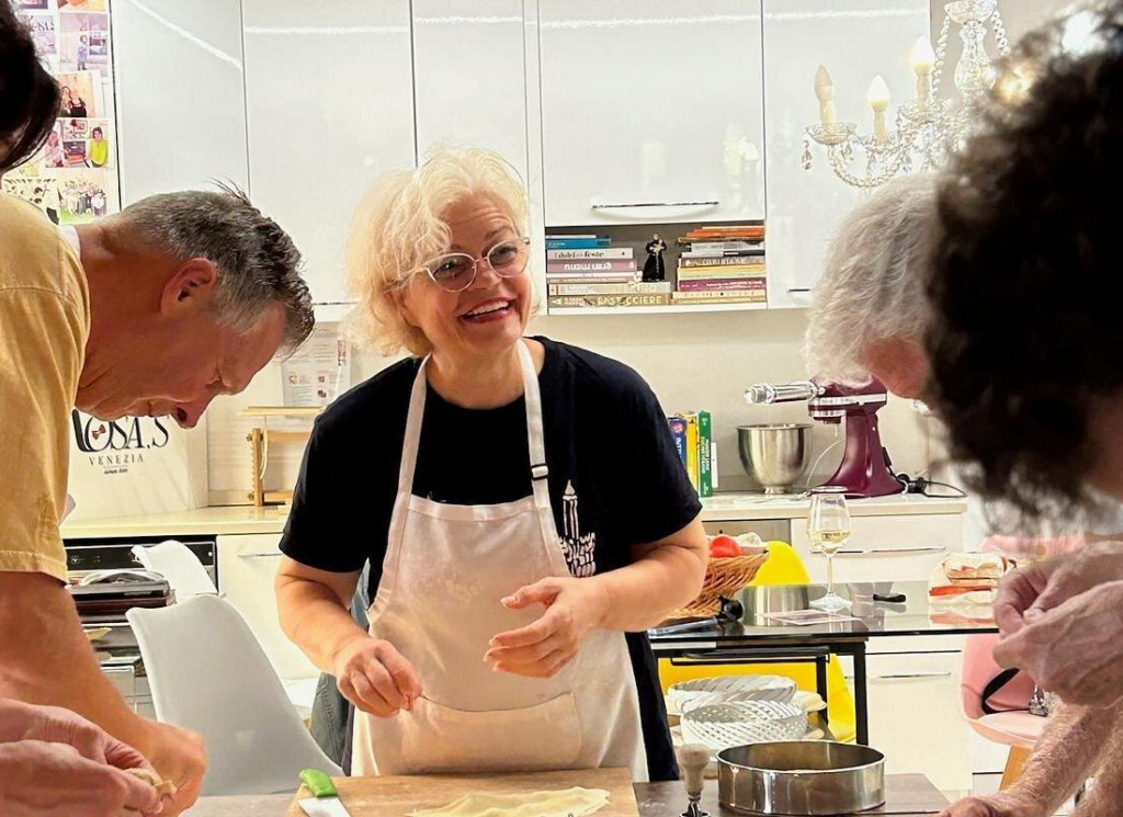 Local Venetian chef guiding participants through fresh pasta preparation in a warm home kitchen setting, authentic hands-on culinary experience featured in the best venice cooking classes.