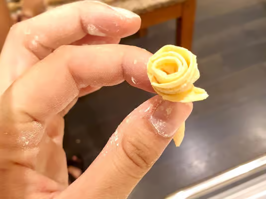 Close-up of handmade pasta shaped into a delicate rose during a traditional Italian culinary workshop, detailed hands-on cooking experience featured in the best venice cooking classes