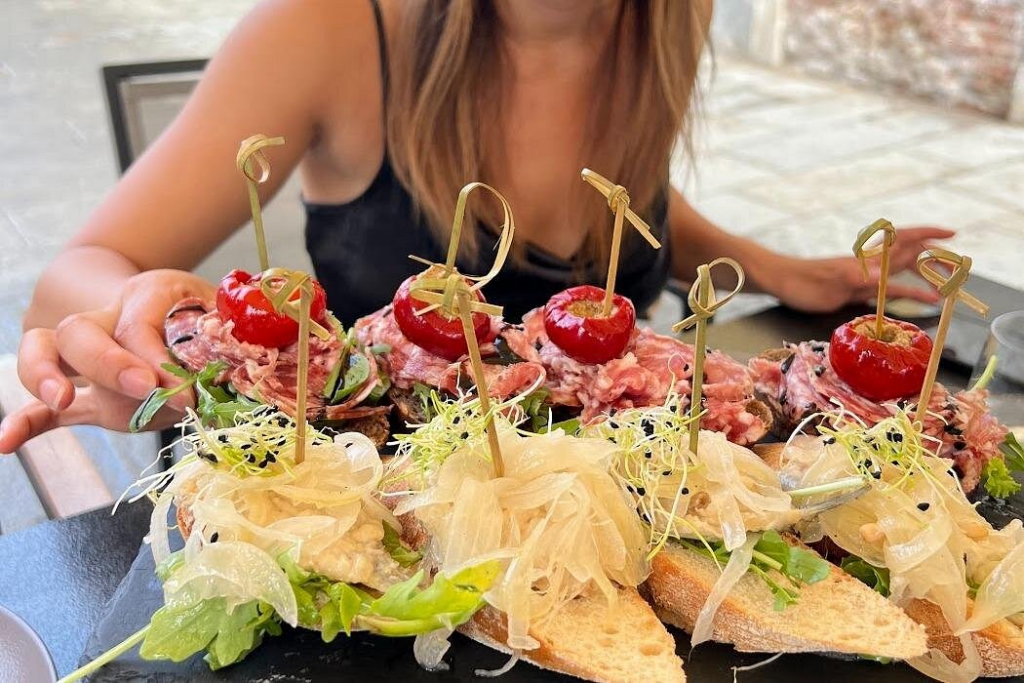 Close-up of gourmet Venetian cicchetti topped with seafood, cured meats, and marinated vegetables on toasted bread, served at a bacaro table, showcasing authentic small-plate tastings commonly experienced on Venice Food And Wine Tours.