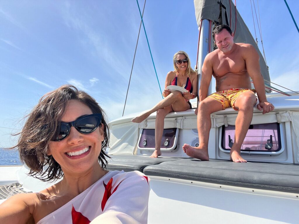 private boat tour Santorini guests relaxing on a luxury sailing yacht, enjoying sunshine and sea views during a private island cruising experience