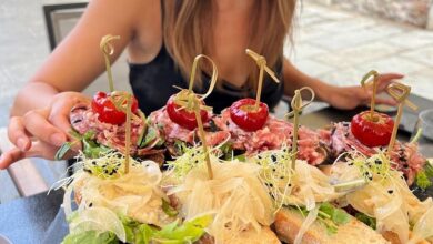 Woman holding a platter of traditional Venetian small bites with seafood, pickled vegetables, and cherry tomato skewers on rustic bread during a venice cicchetti tour in a local bacaro.