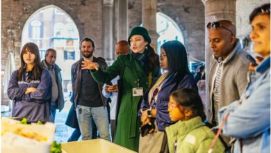 Local guide explaining fresh seafood and regional specialties to visitors inside a historic Venetian market, a hands-on cultural experience typical of a venice market tour.