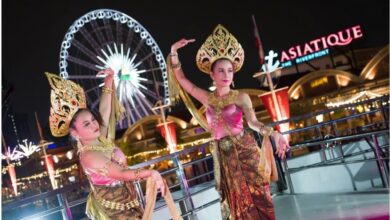 Thai cultural dancers performing on a dinner cruise Bangkok experience near Asiatique The Riverfront with the Ferris wheel illuminated at night