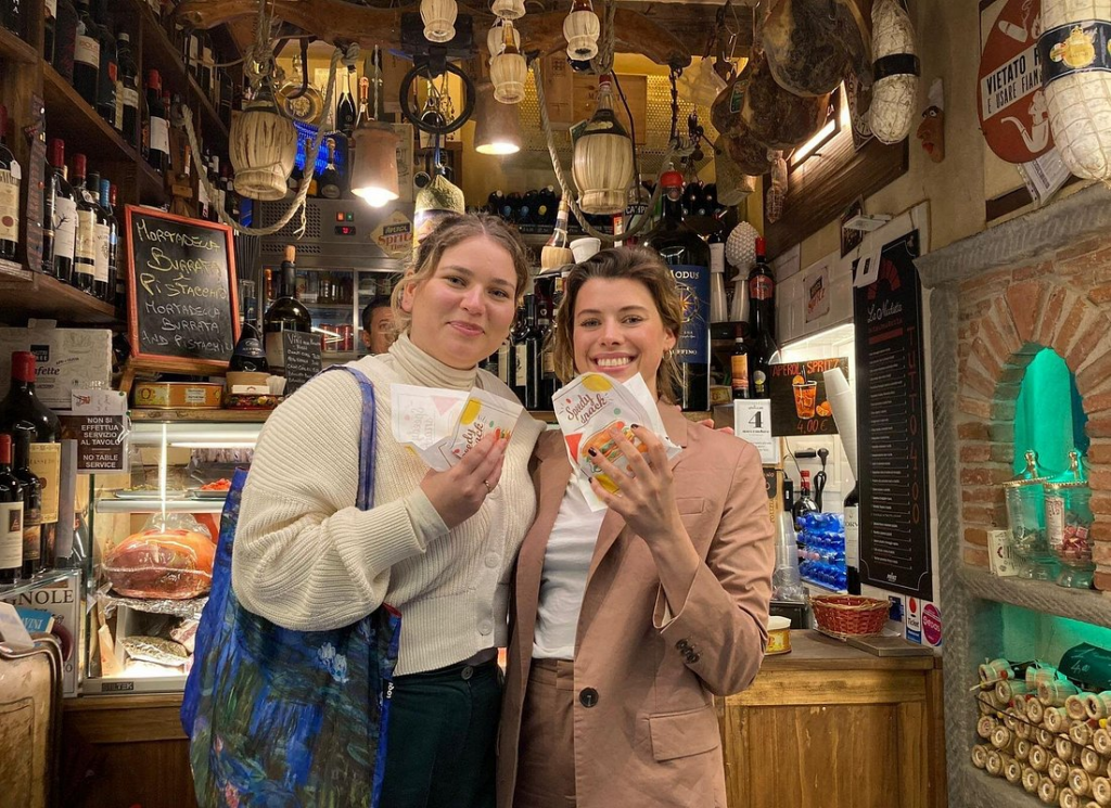 Two travelers enjoying local Italian snacks inside a traditional wine bar during a florence food and wine walking tour in Florence.