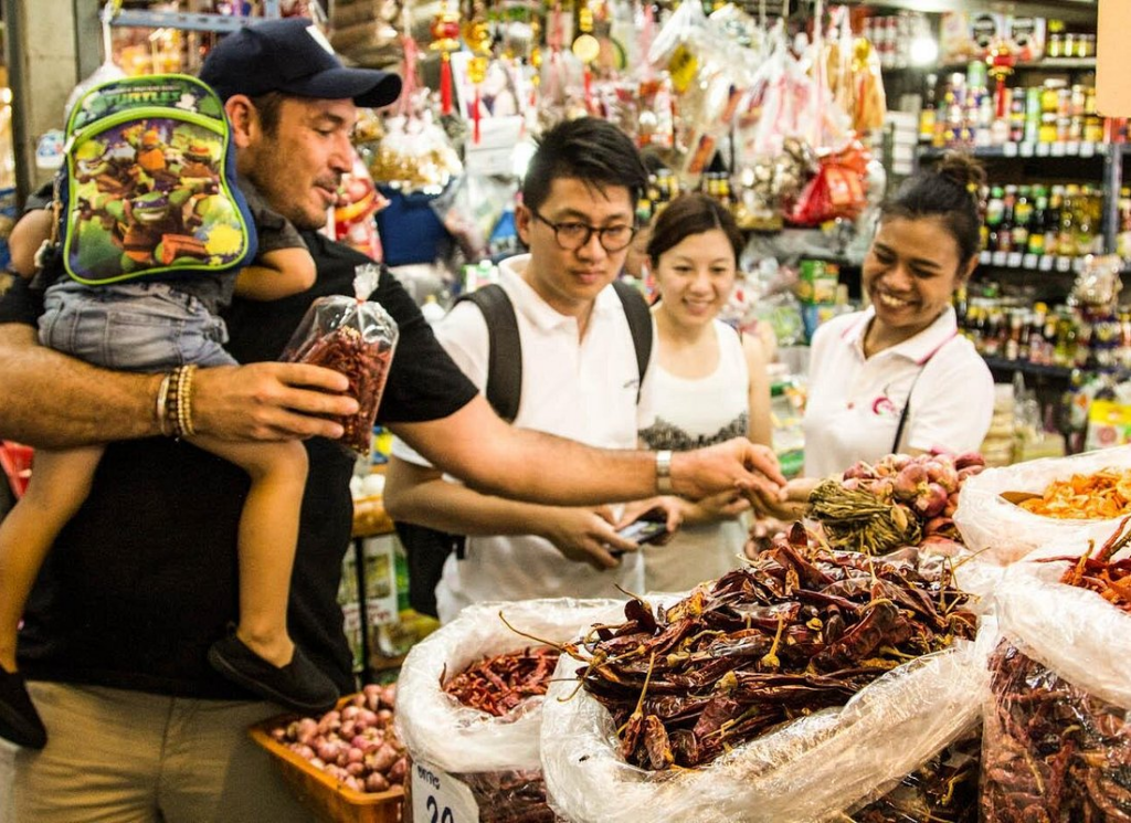 Students selecting dried chilies at a local market during one of the Best Thai Cooking Classes in Bangkok