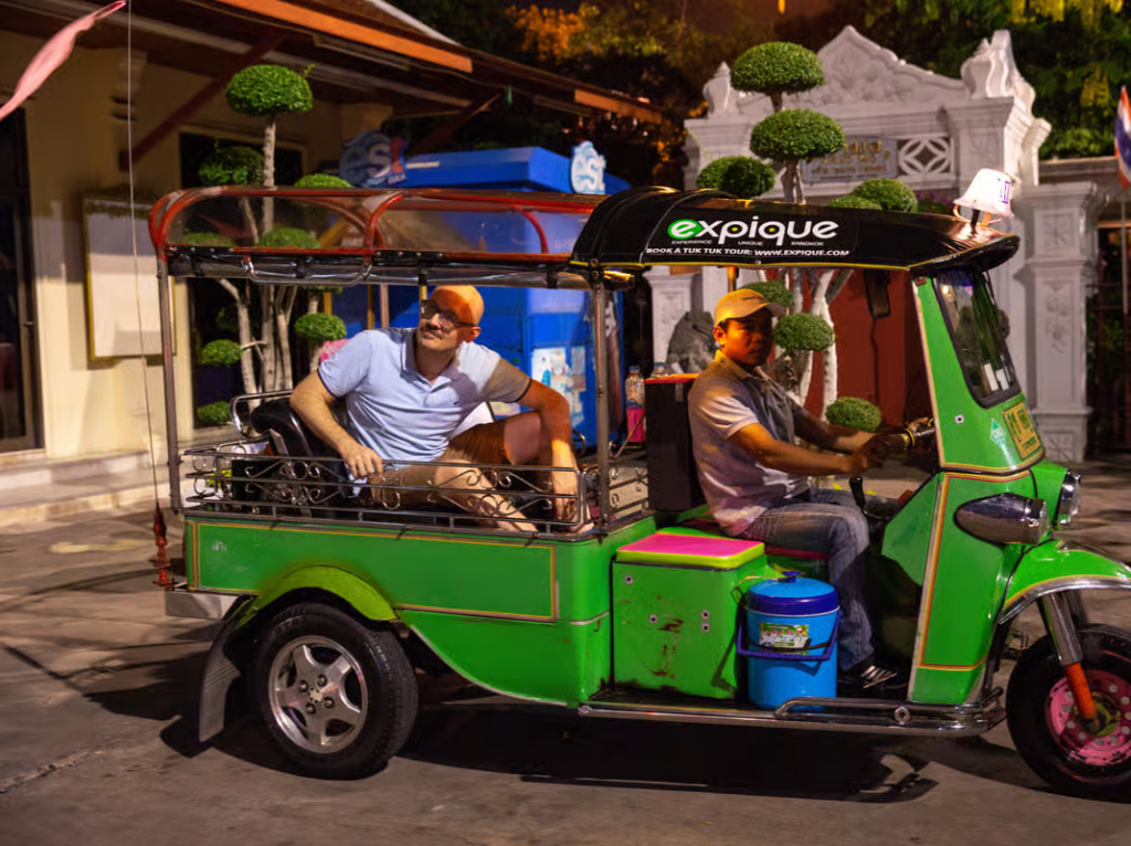 Traveler riding through Bangkok streets in a colorful tuk tuk during a guided tuk tuk food tour Bangkok