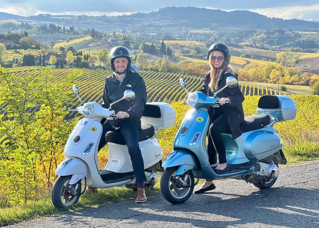 Couple riding Vespa scooters through Tuscan vineyards on a Florence food and wine tour