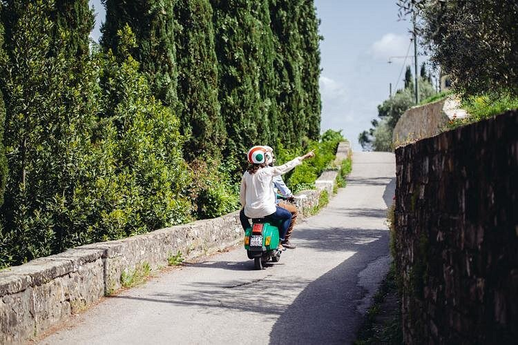 Couple riding a Vespa along a quiet countryside road on a vespa tour Florence