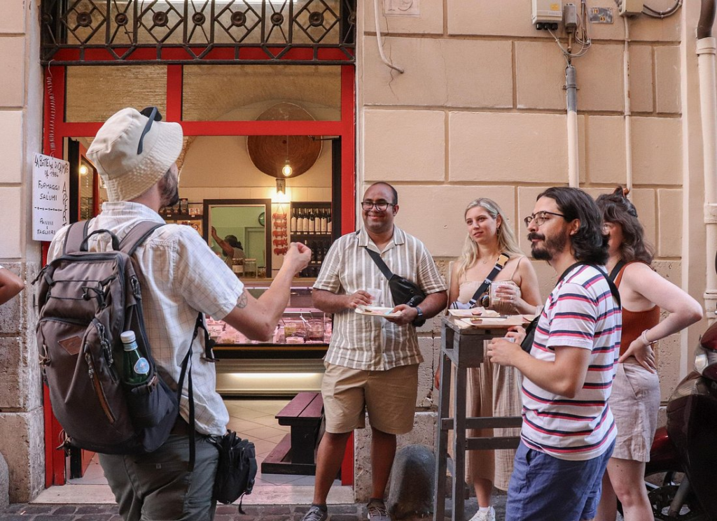 Guide explaining local dishes to a group on rome street food tours outside a small food shop in Rome