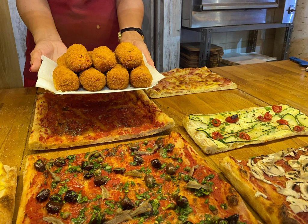 Fresh pizza al taglio and fried suppli served on rome street food tours at a local Rome street food shop