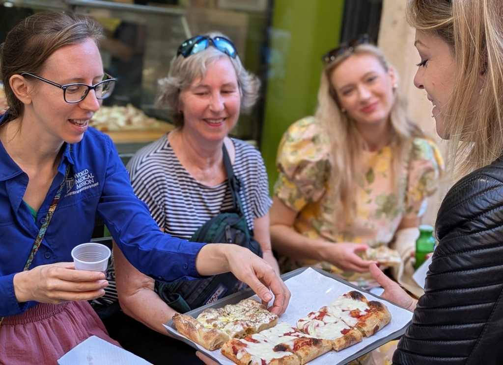 Travelers enjoying pizza slices on rome street food tours at a local street food spot in Rome