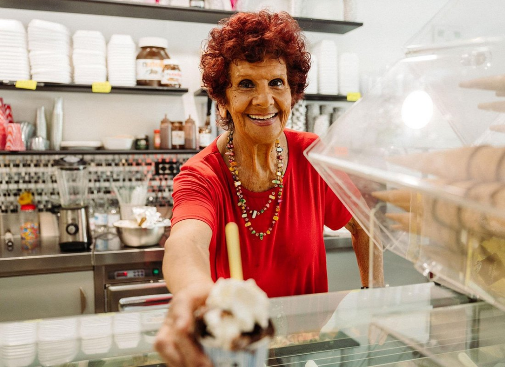Smiling vendor handing over a dessert on rome street food tours inside a traditional Rome gelato or pastry shop