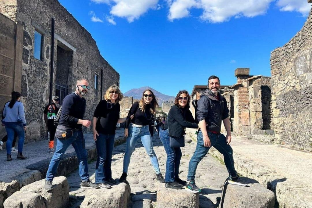 Travelers exploring ancient Pompeii ruins with Mount Vesuvius in the background on wine tours from Rome
