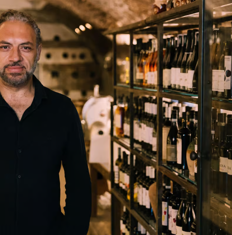 Wine tasting Rome experience with a sommelier standing in a cellar surrounded by shelves of Italian wine bottles