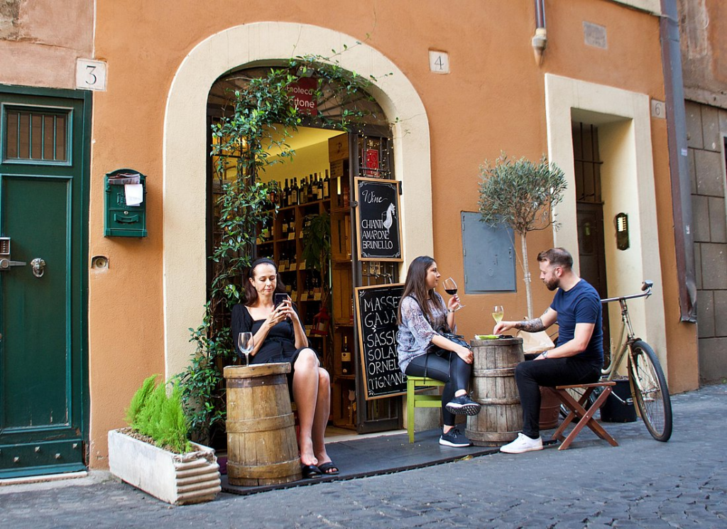 Wine tasting Rome experience outside a small wine bar with people sitting at tables and enjoying Italian wine