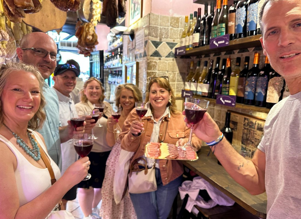 Group enjoying wine and cured meats during rome market tours inside a traditional Rome deli shop