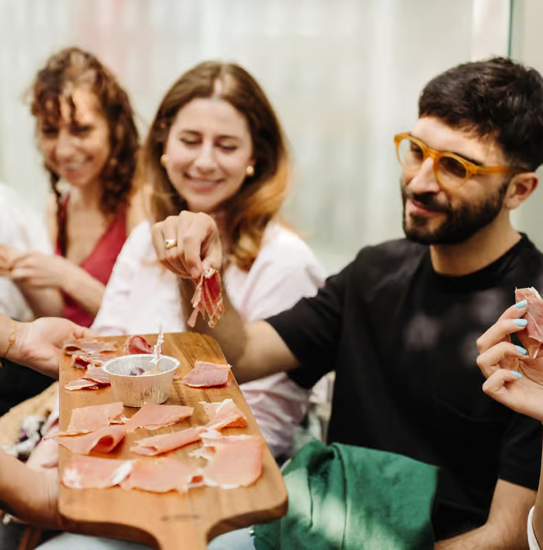 Travelers sampling prosciutto and local delicacies on rome market tours during a food tasting experience in Rome