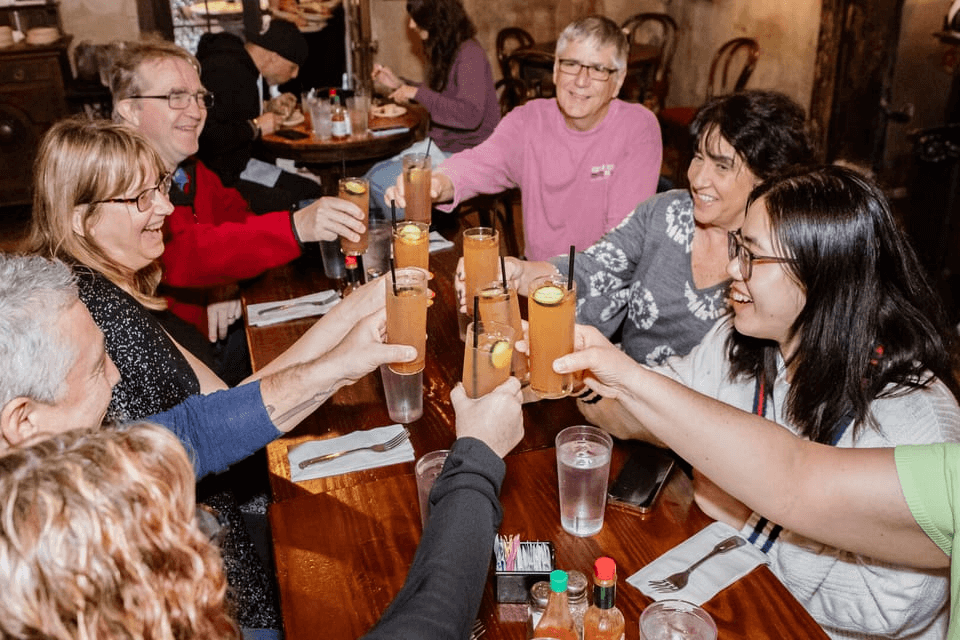 Friends raising classic cocktails in a lively French Quarter bar during a New Orleans cocktail tour.