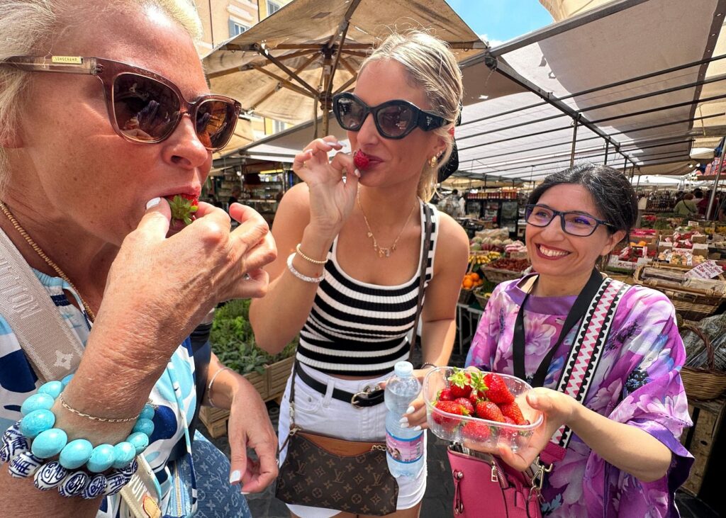 Travelers tasting fresh strawberries on rome street food tours at a bustling outdoor market in Rome