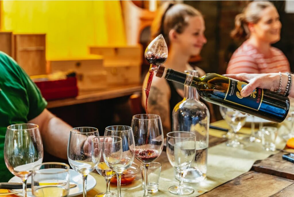 Guests enjoying a guided tasting on wine tours from Rome as red wine is poured into glasses at a rustic Italian winery