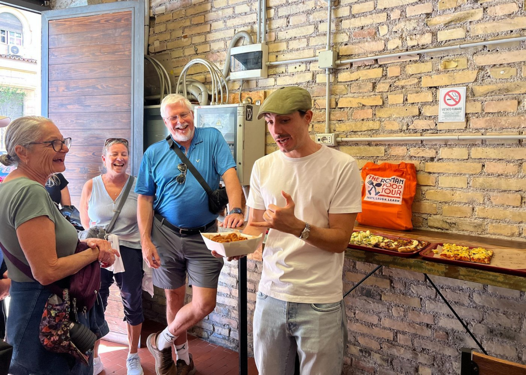 A local guide explaining traditional Roman street food as guests sample authentic Italian specialties on a rome market tour at a bustling outdoor market in Rome