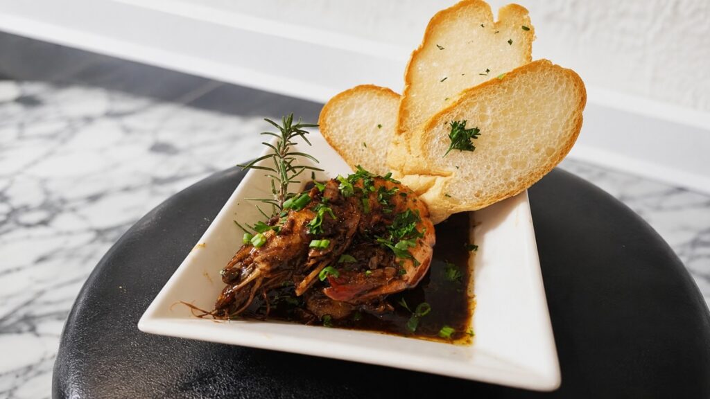 Classic New Orleans barbecue shrimp served with toasted French bread during a cooking class New Orleans experience.