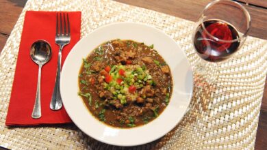 A bowl of authentic Cajun gumbo served over rice with a glass of wine during a cooking class New Orleans experience.