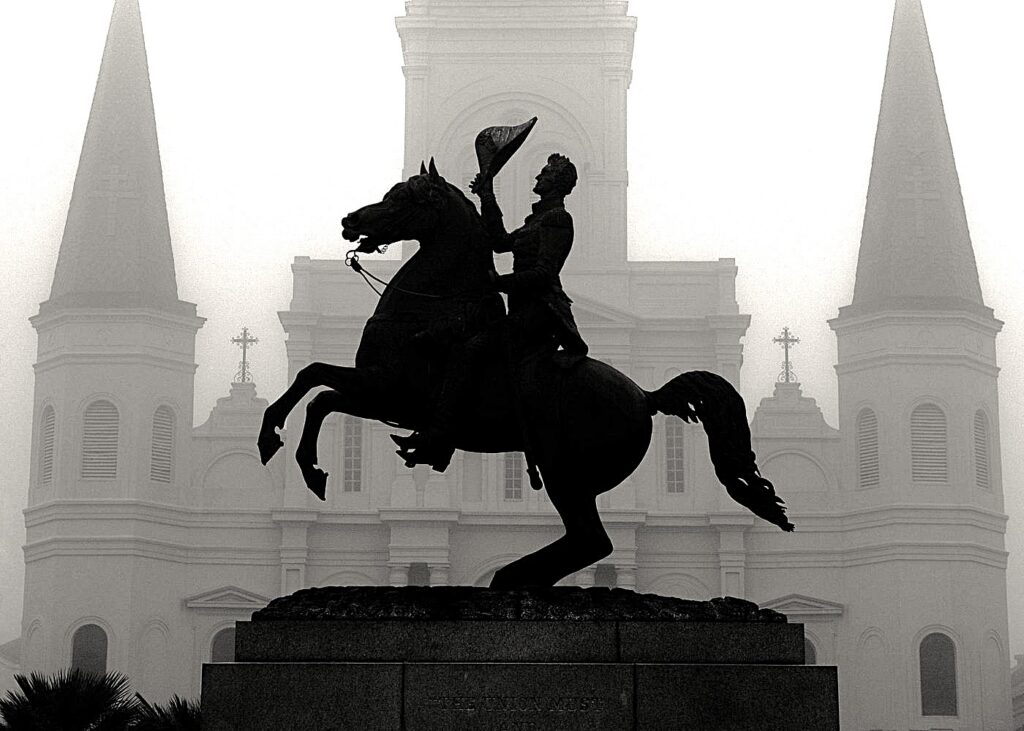 Haunted pub crawl New Orleans featuring the Andrew Jackson statue silhouetted in front of St. Louis Cathedral on a foggy night in Jackson Square.