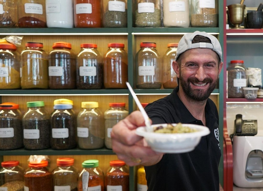 tel aviv food tours include tasting authentic hummus served by a local vendor surrounded by colorful spices and traditional ingredients in Tel Aviv.
