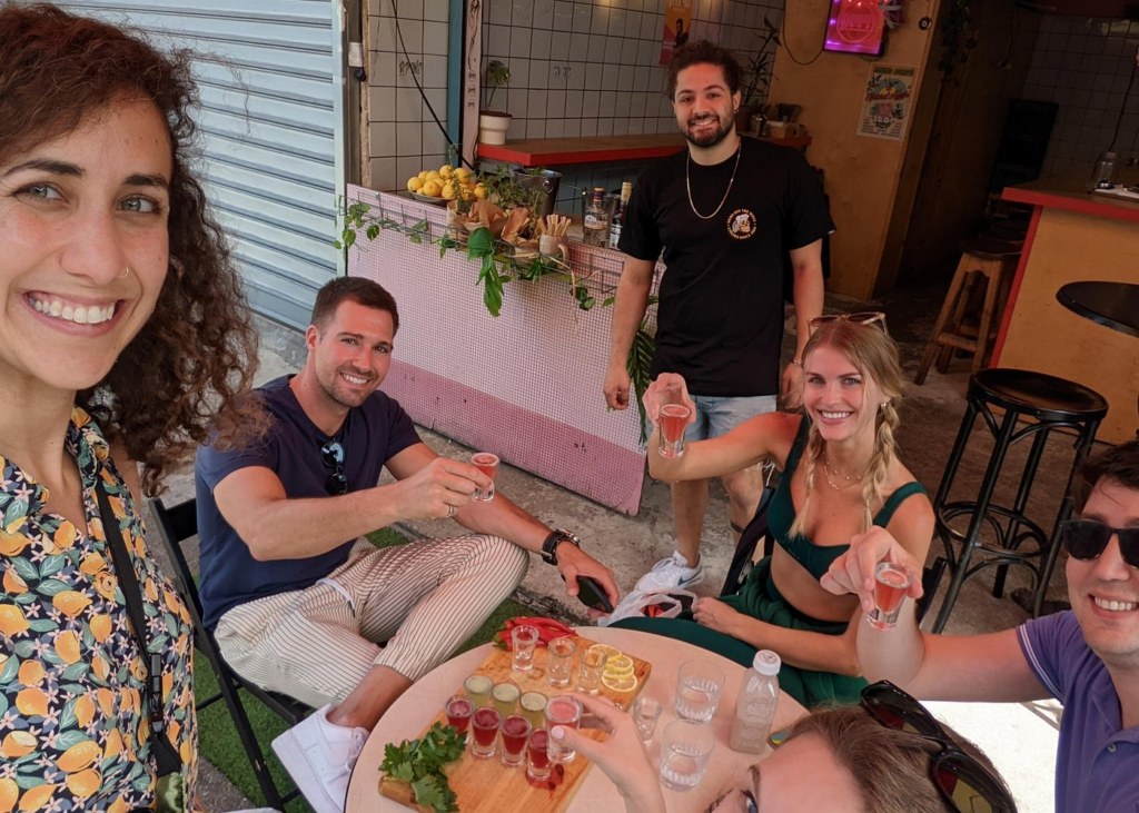 Travelers enjoying food and drinks at a Tel Aviv café during a guided tasting experience on one of the best Israel food and market tours.