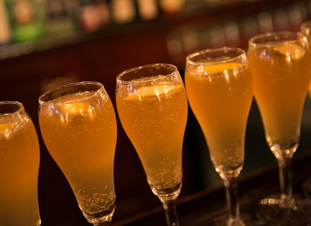 Sparkling French 75 cocktails lined up at a historic bar during a New Orleans cocktail tour through the French Quarter.