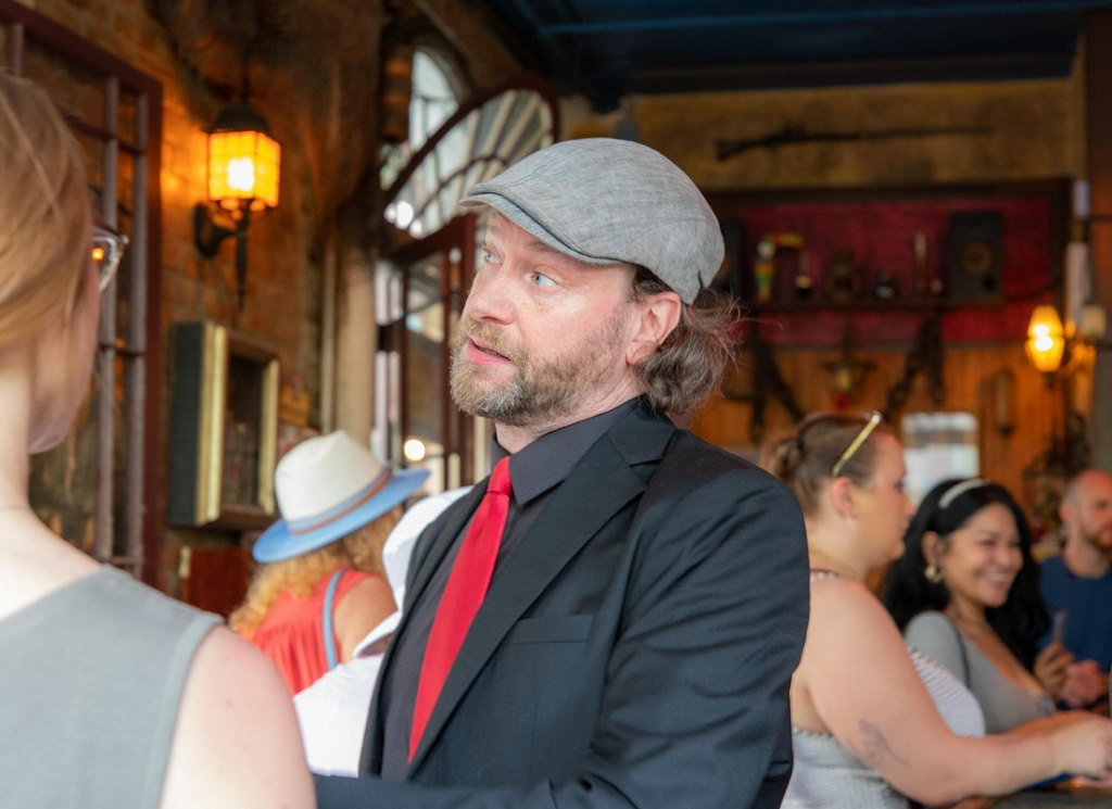 A knowledgeable guide sharing cocktail history with guests inside a historic bar on a New Orleans cocktail tour.
