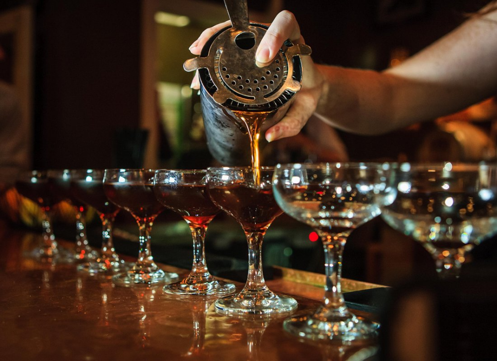 A bartender pouring handcrafted cocktails into coupe glasses at a historic bar on a New Orleans cocktail tour.
