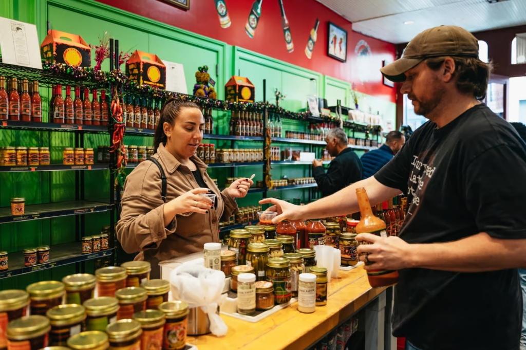 Guest sampling Louisiana hot sauce and local specialties inside a gourmet food shop on one of the best food tours in New Orleans.