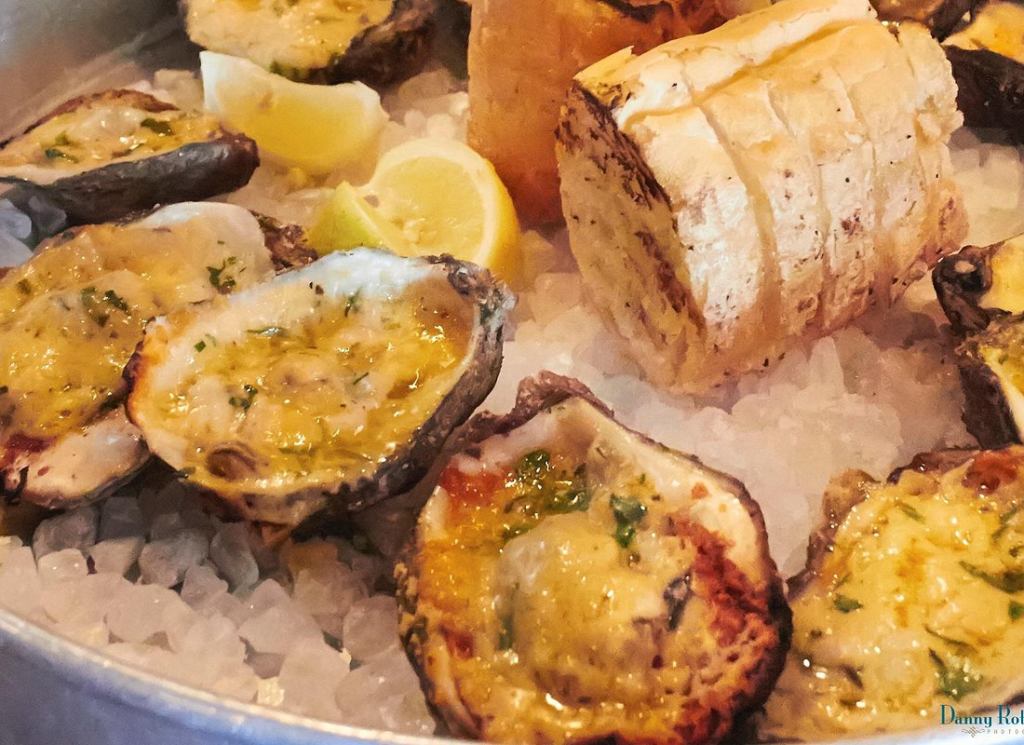 Chargrilled oysters served on ice with garlic butter, lemon, and French bread, a must-try stop on the best food tours in New Orleans.