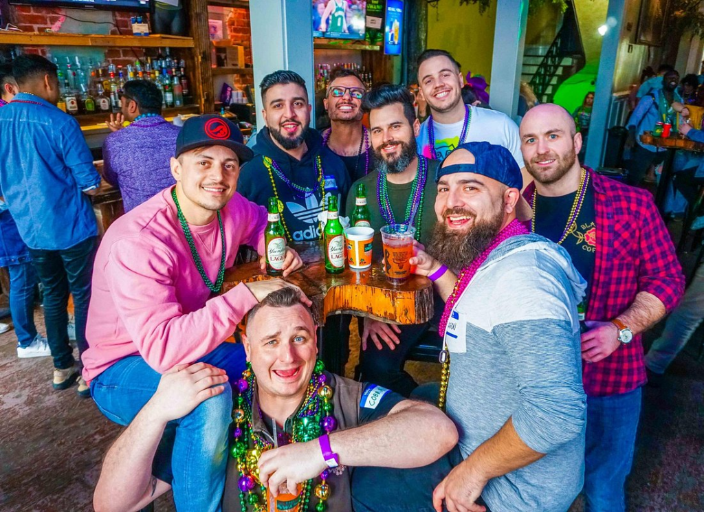 Group of friends enjoying beers and cocktails inside a lively French Quarter bar during a new orleans pub crawl.