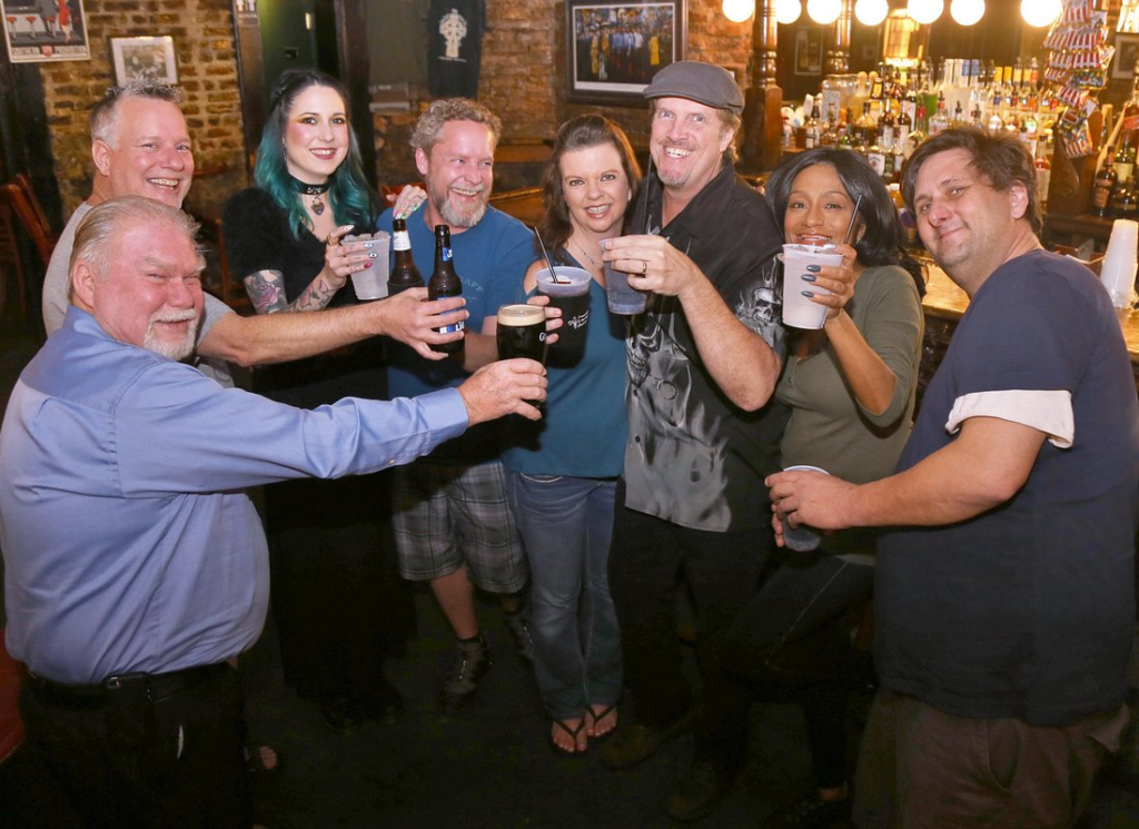 Haunted pub crawl New Orleans with a lively group raising drinks inside a historic French Quarter bar during an evening ghost and pub tour.