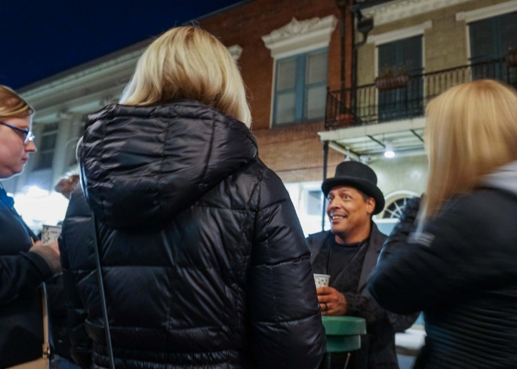 Haunted pub crawl New Orleans with a costumed guide sharing ghost stories to a group during a nighttime walking tour through the French Quarter.