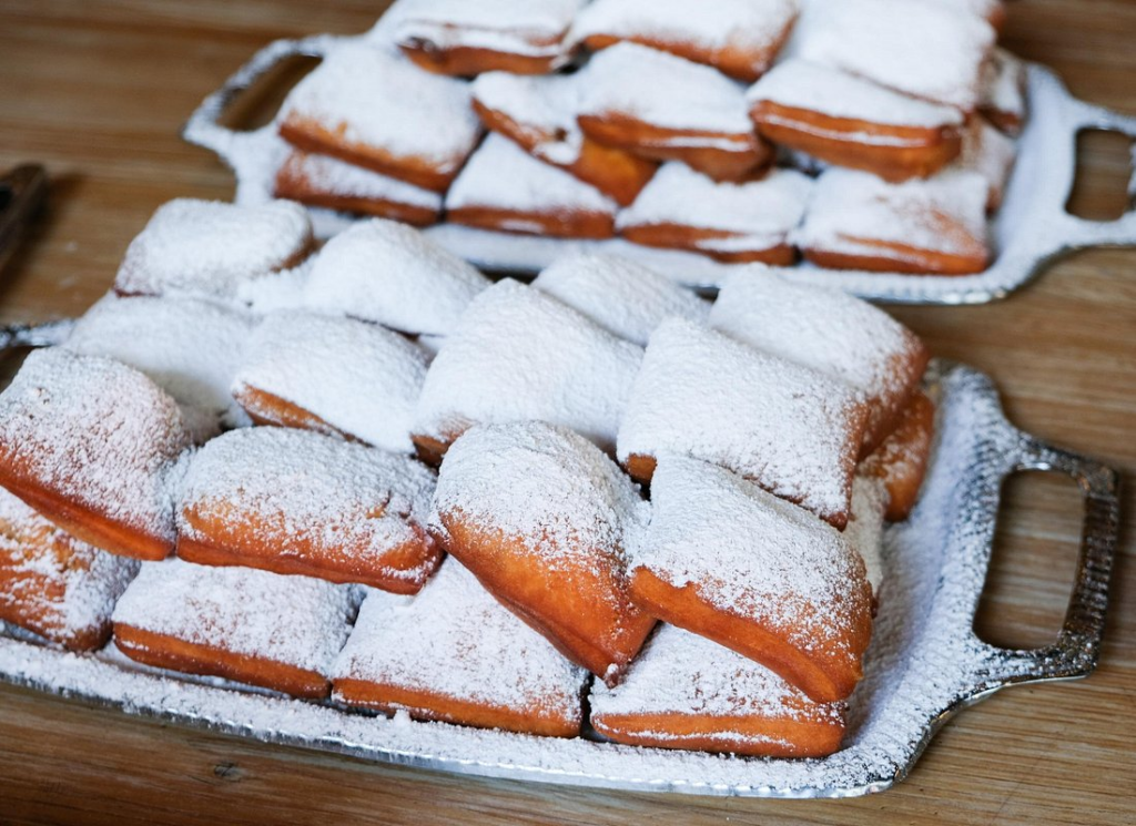 New Orleans food walking tour featuring fresh beignets dusted with powdered sugar, a must-try sweet treat at one of the city's iconic cafés.
