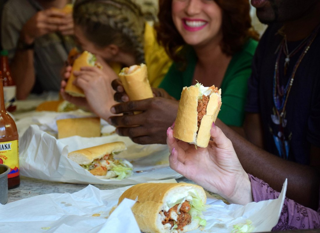 Guests enjoy classic New Orleans po’boys together during a French Quarter food tour, sampling one of the city's most iconic sandwiches in a lively local restaurant.