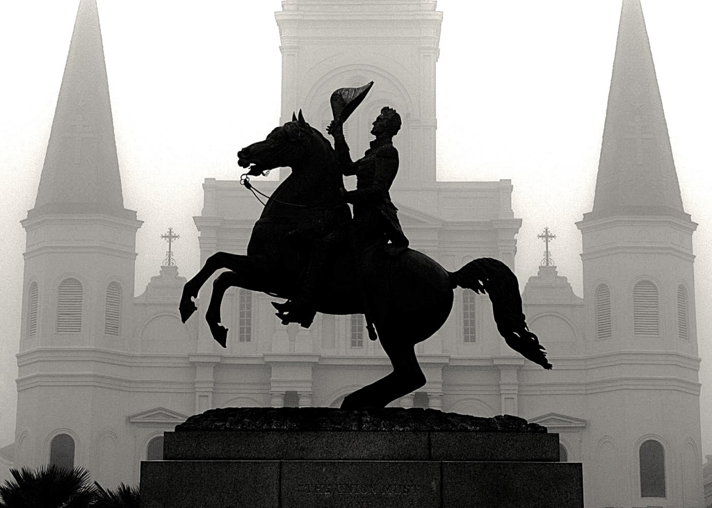 Haunted pub crawl New Orleans featuring the Andrew Jackson statue silhouetted in front of St. Louis Cathedral on a foggy night in Jackson Square.