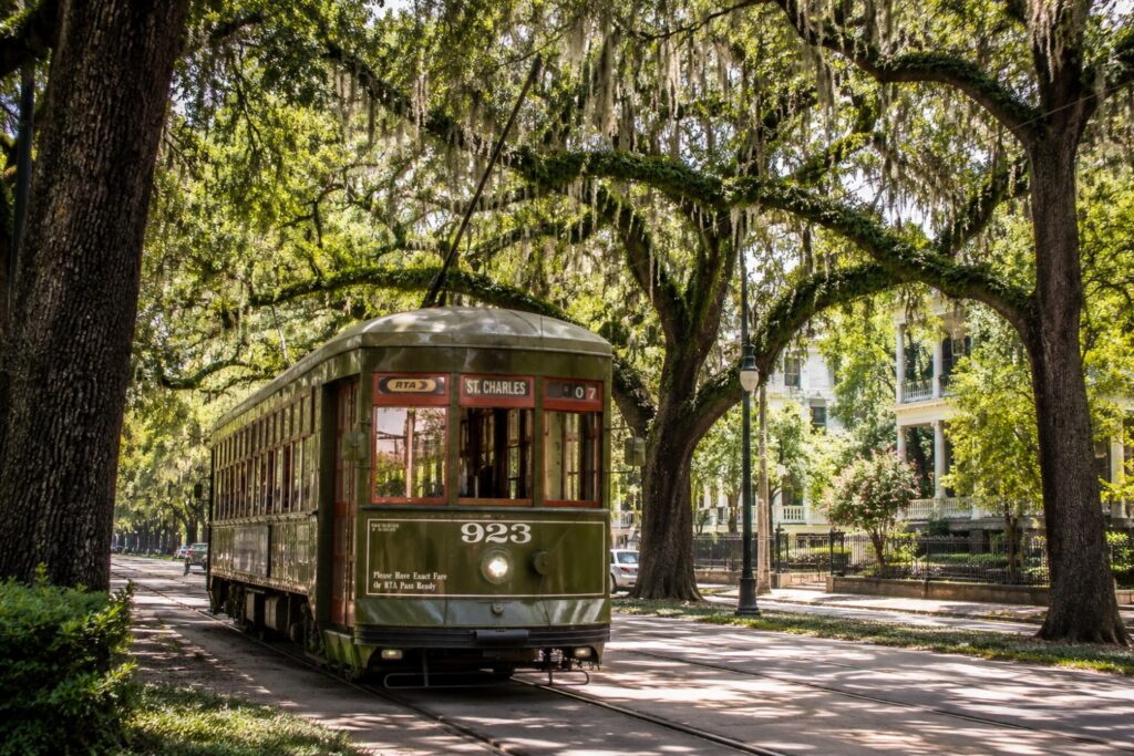 The historic St. Charles streetcar traveling beneath oak trees toward the Garden District, a key stop in any New Orleans travel guide.
