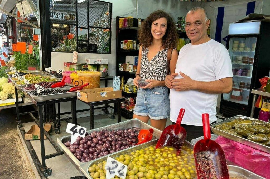 tel aviv food tours exploring a vibrant market stall with local vendors, olives, pickled vegetables, and traditional Mediterranean delicacies in Tel Aviv.